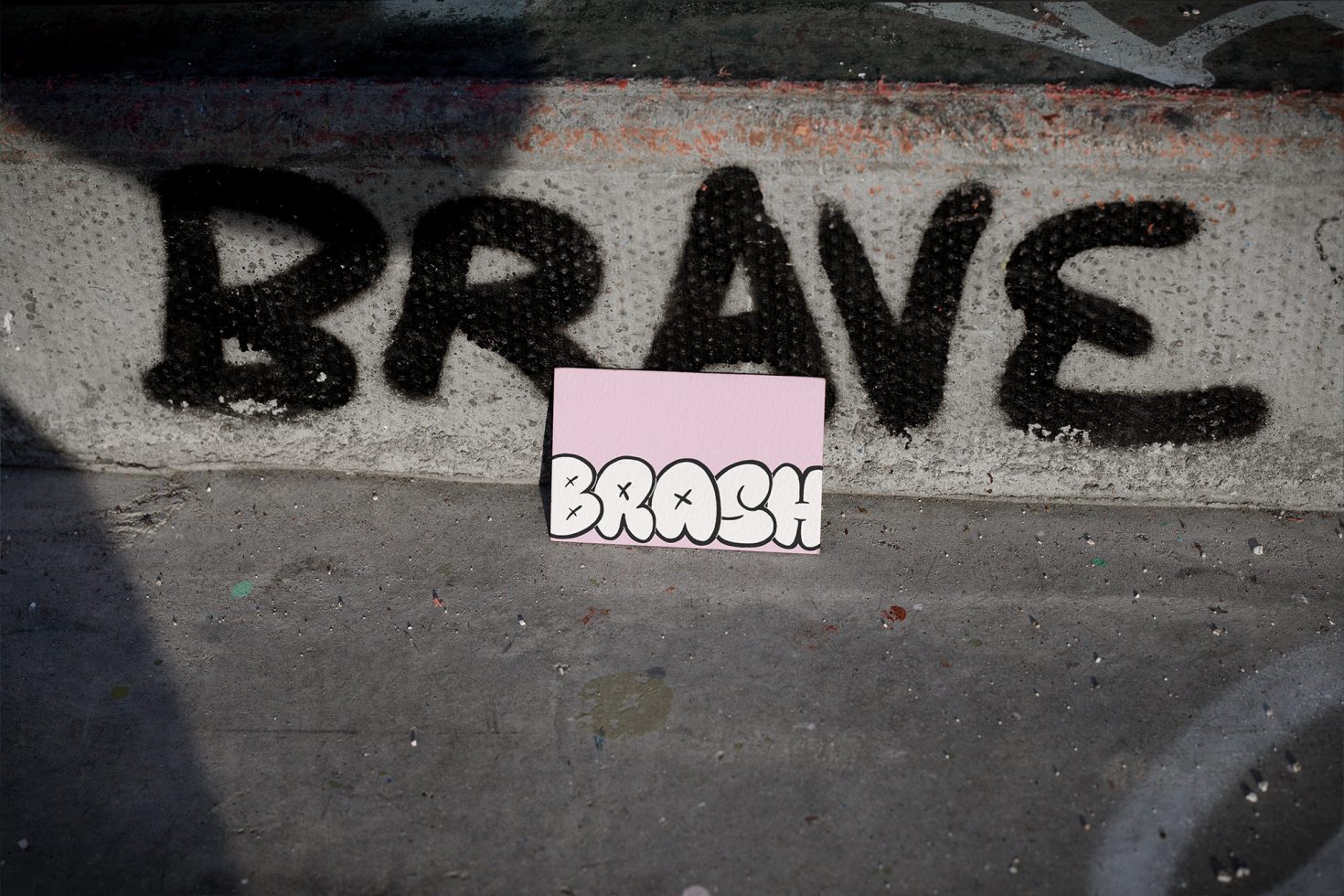 Urban stencil graffiti mockup with the word BRAVE on a wall and a paper overlay text BRUSH for design asset presentation.